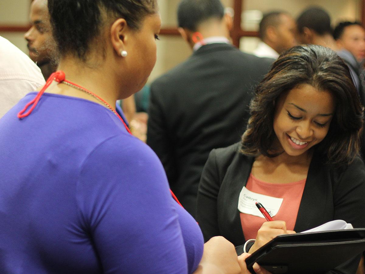 Smiling student writing down notes from a conversation with employer